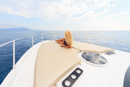 Young sexy woman lies in white dress enjoying clouds in the sky on yacht at the sea near faraglioni island capri italyの写真素材