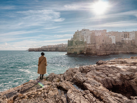 Woman isolated on the rocks looking Polignano a mare in winter seasonの写真素材