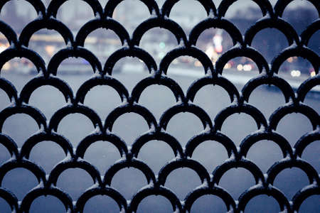 wrought iron lattice on the bridge over the river in the evening cityの写真素材