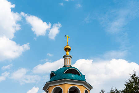 Golden dome of the Orthodox church and the bird on the blue sky and clouds background
