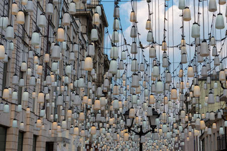 Decoration of the street with garlands. Old architecture and metal black lights. Selective focus.の写真素材