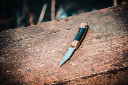 A pocket knife on the old Board. Selective focus. Tint. Close up.