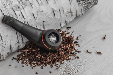 Smoking tobacco pipe on natural wooden background with space for lettering or design. Close-up.の写真素材