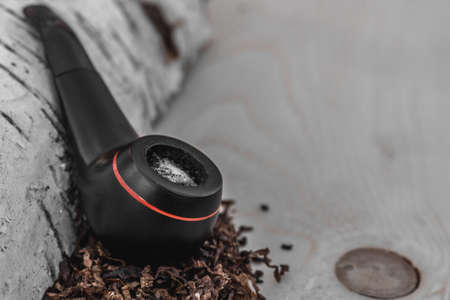 Smoking tobacco pipe on natural wooden background with space for lettering or design. Close-up.