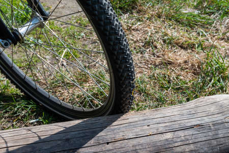 Close-up of a bicycle wheel parked by an old big log