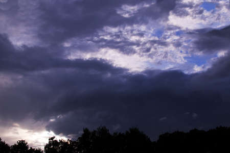 Abstract landscape. The setting sun against the background of the forest and thunderclouds. Soft...