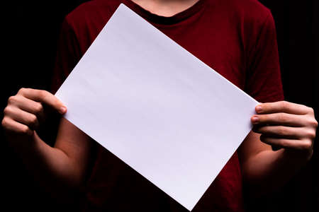 Paper sheet in the hands of a young person. Close-up. Space for lettering and designの写真素材