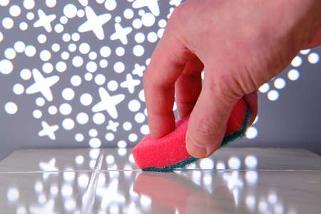 Hand with unhealthy skin wipes the surface with a pink washing sponge. Cleaning concept. Close-up. Selective focusの写真素材