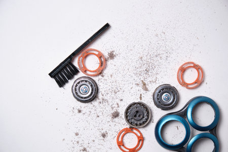 Details of a disassembled dirty shaver head and a cleaning brush on a light background. Soft selective focus. Copy spaceの写真素材