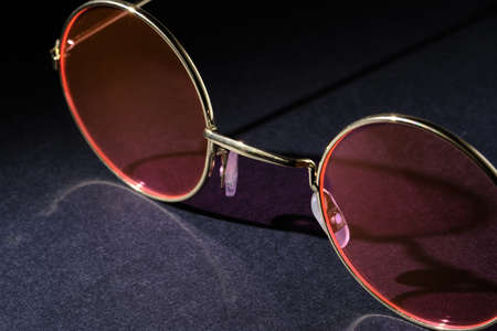 Close-up of glasses with pink lenses on a dark background. Selective focus. Minimal design with copy spaceの写真素材