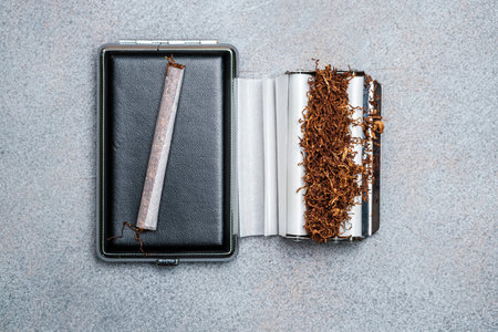 Cigarette, cigarette case and machine for making rolls with tobacco. Close-up. View from above. Selective focusの写真素材