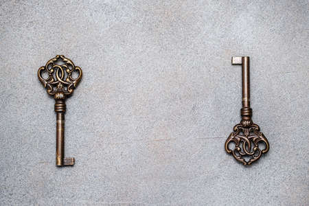 Two old vintage bronze keys on an abstract gray background. View from above. Space for lettering and...