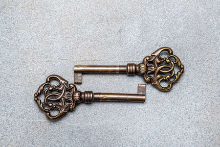 Two old vintage bronze keys on an abstract gray background. View from above. Space for lettering and...