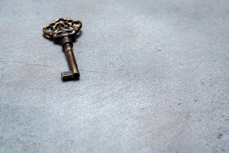 Old bronze key on an abstract gray background. Selective focus. Space for lettering and designの写真素材