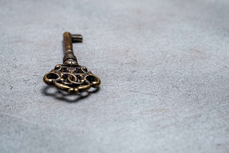 Old bronze key on an abstract gray background. Selective focus. Space for lettering and designの写真素材