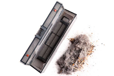 Dust and debris and a container from a robot vacuum cleaner on a light background. House cleaning results. Close-up. Selective focusの写真素材