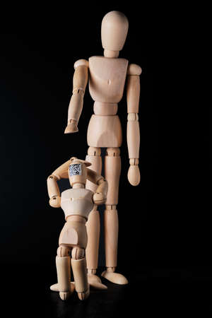 Two wooden mannequins on a dark background. Selective focus. The concept of the trend of assigning...