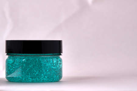 Closed jar with a turquoise cosmetic gel on a light background. Close-up. Selective focusの写真素材