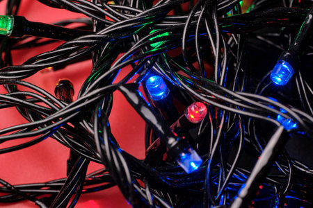 Close-up of wires with multicolored LED bulbs on a red-black background. selective focus.の写真素材