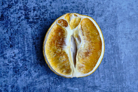 Half of a dried orange on an abstract blue background. close-up. selective focus.