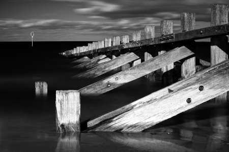 Horizontal black   white image of wooden wave breakersの写真素材