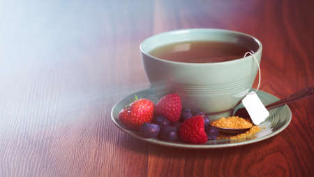 Cup of fruit tea with strawberries, raspberries and blueberries on wooden table, with copy spaceの写真素材