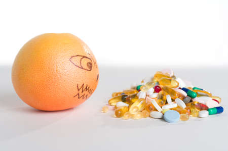 Pink grapefruit and pills, vitamin supplements on white background with copy space, healthy diet...