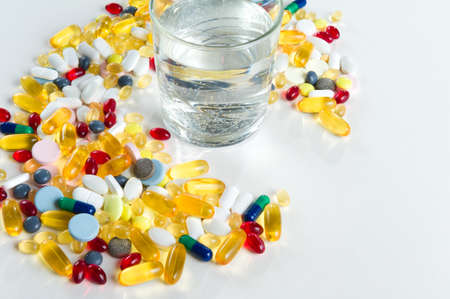 Colorful pills and glass of water, on white backgroundの写真素材