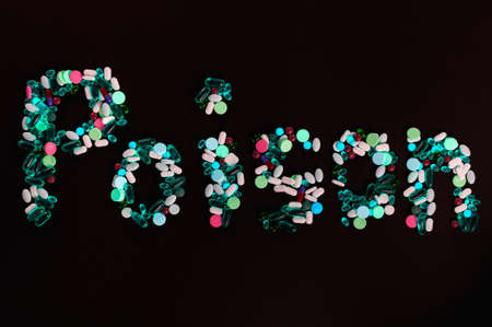 Tablets, pills and capsules, that create word poison, on black background