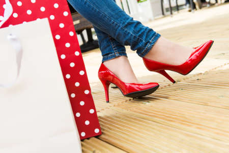 Attractive young female in sexy red high heels enjoying a break after succesfull shopping, detail shot, with copy space の写真素材