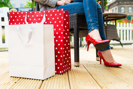Attractive young female in sexy red high heels enjoying a break after succesfull shopping, detail shot, with copy space の写真素材