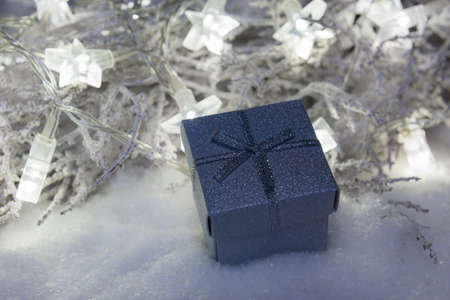 Silver christmas present box in snow with star lights defocused in the background, christmas background, bannerの写真素材