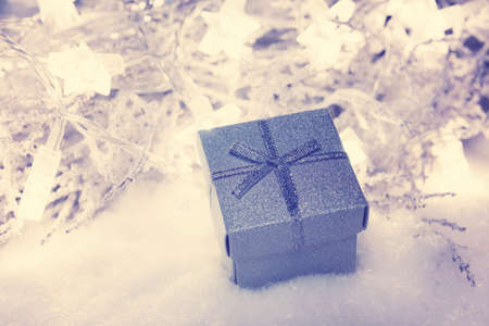 Silver christmas present box in snow with star lights defocused in the background, christmas background, bannerの写真素材