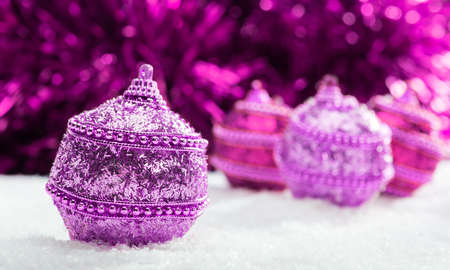 Pink and purple Christmas balls in snow with tinsel, christmas background, christmas bannerの写真素材