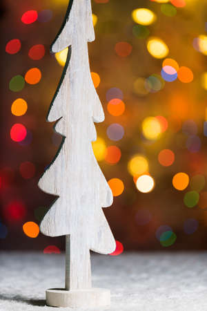Rustic white wooden tree decoration standing in snow, with christmas tree lights, bokeh background and copy space, festive bannerの写真素材
