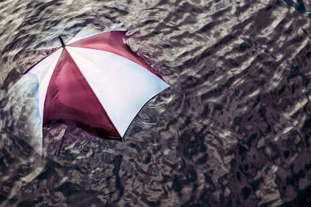 Raining too much ... Escape the bad weather, vacation concept. Umbrella swimming in water.の写真素材