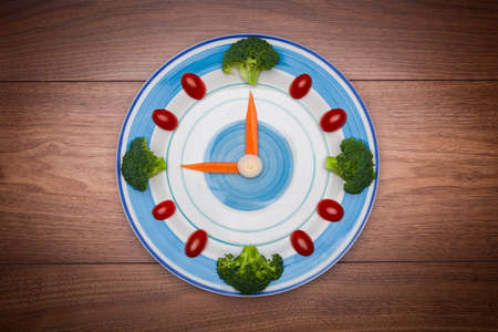 Food clock with vegetables, Healthy food concept, on wooden table with copy space