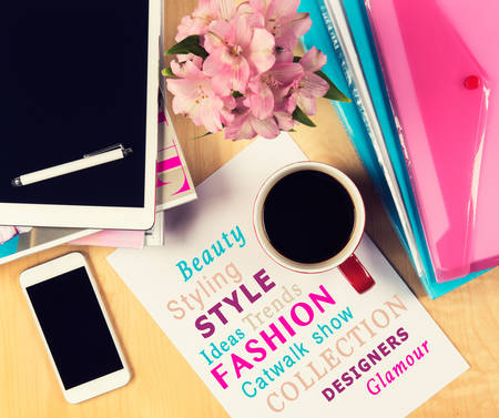 Office table with fashion magazines, digital tablet, smartphone and cup of coffee. View from above with copy spaceの写真素材