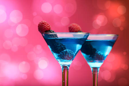 Colourful cocktails garnished with berries, background with light effectsの写真素材