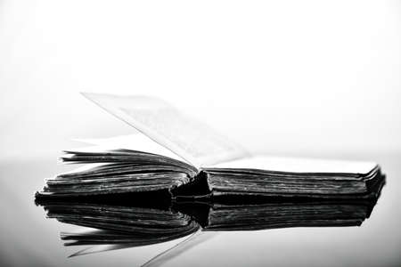 High contrast black and white image of an old book on black reflective surfaceの写真素材
