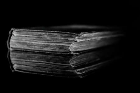 High contrast black and white image of an old book on black reflective surfaceの写真素材