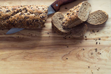 baguette rye bread sprinkled with various seeds on a wooden boardの写真素材