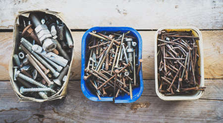 Boxes of old rusty metal screws on wooden backgroundの写真素材