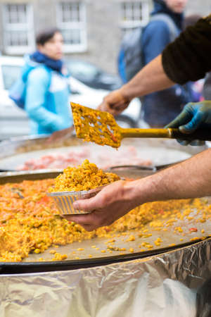Man serving traditional spanish chicken paella, food marketの写真素材