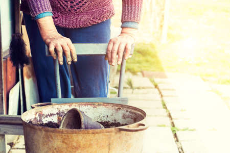 Old woman filling a pot with fresh soil. Symbol of spring and clean eating concept.の写真素材