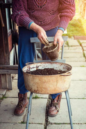 Old woman filling a pot with fresh soil. Symbol of spring and clean eating concept.の写真素材