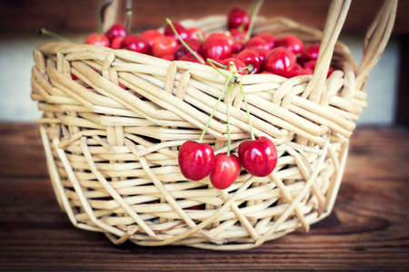 Ripe organic homegrown cherries in a basket, on wooden backgroundの写真素材