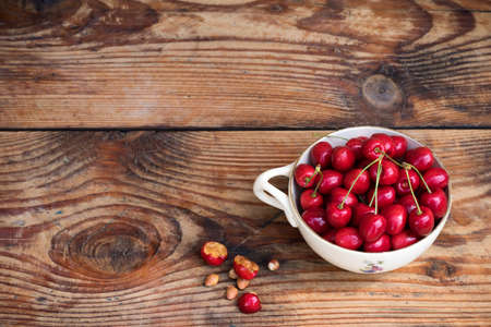 Ripe organic homegrown cherries and stones in a vintage ceramic bowl, on wooden backgroundの写真素材