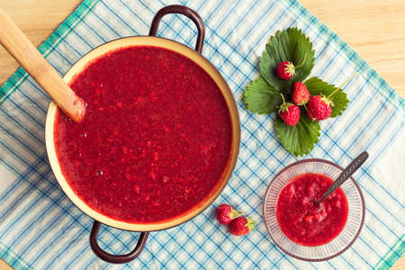 Homemade strawberry jam (marmelade) cooking. Large pot with hot jam and fresh strawberriesの写真素材