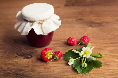 Homemade strawberry jam (marmelade) in jars on wooden background.の写真素材